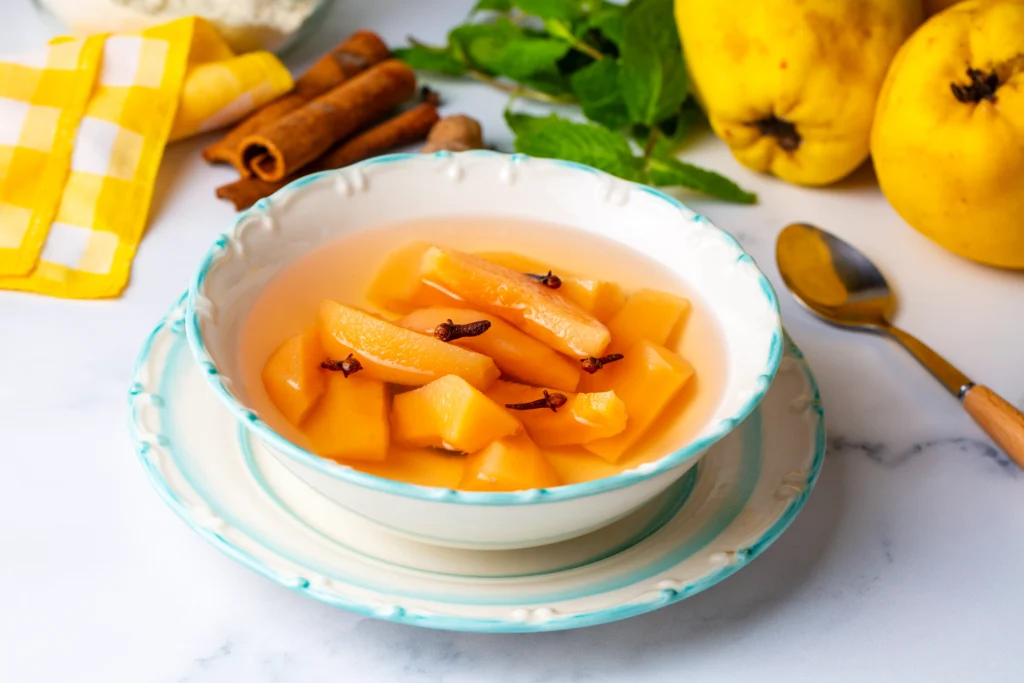 Compota de membrillos sin azúcar con membrillos frescos y palitos de canela de fondo