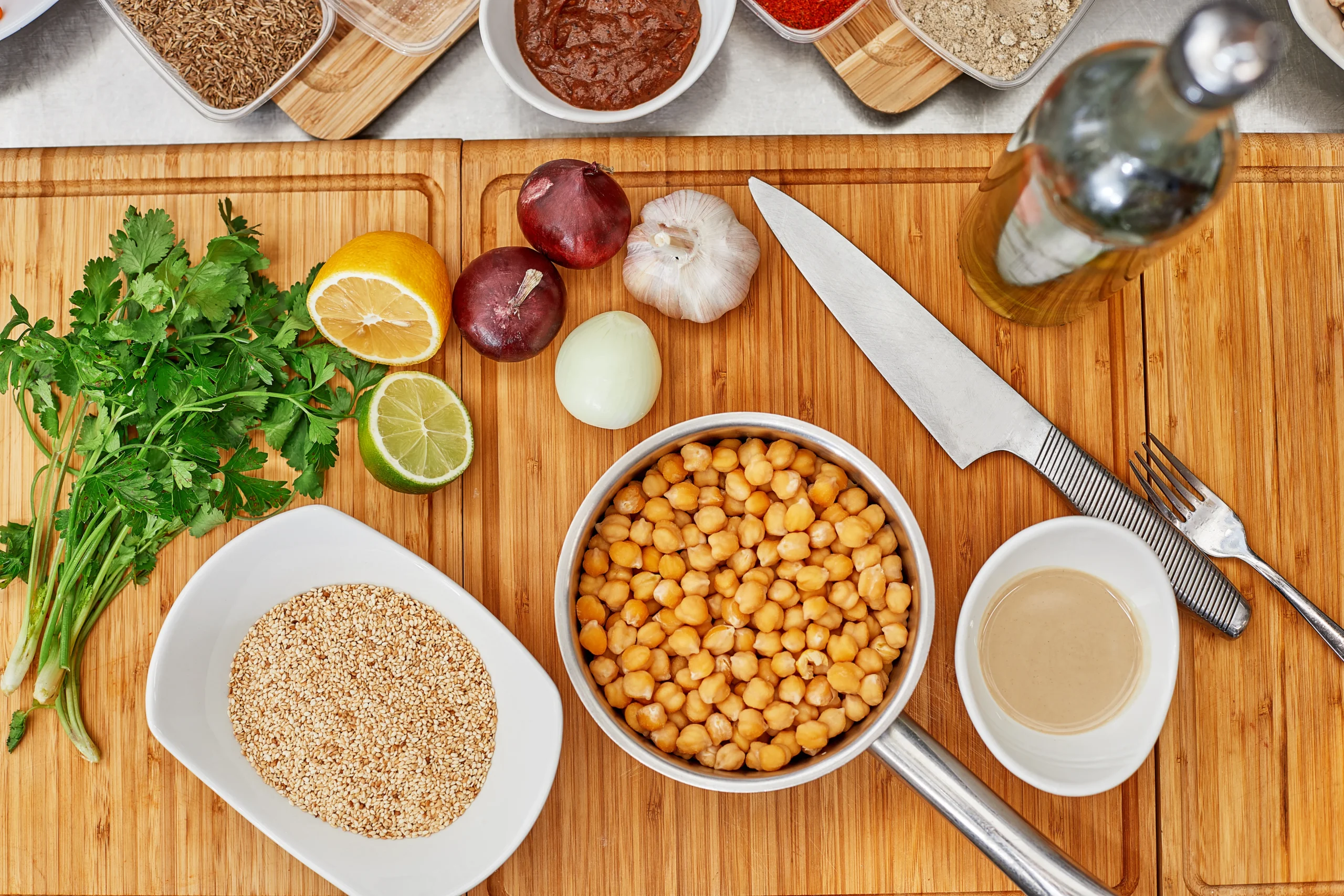 Mise en place para hamburguesas veganas de garbanzos saludables: garbanzos cocidos, cebolla picada, zanahoria rallada, cilantro, harina de avena y especias.