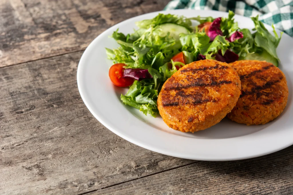 Hamburguesas veganas de garbanzos saludables servidas sobre una ensalada fresca.